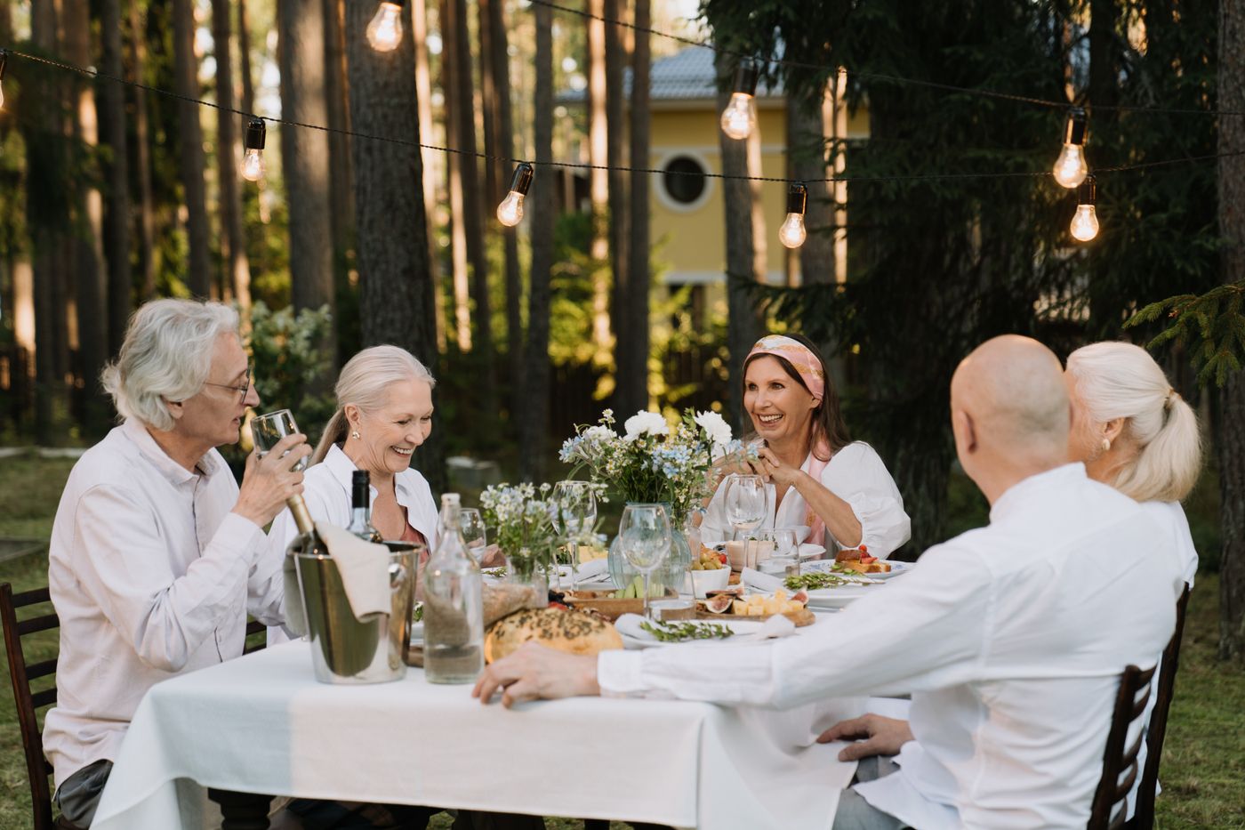 Un groupe d'amis de plus de 50 ans partage un dîner convivial en terrasse au coucher du soleil